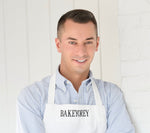 Louis wearing a blue and white striped shirt with a white apron with Bakeyorey embroidered on it 
