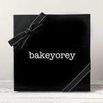 Black gift box with black ribbon and white logo reading Bakeyorey